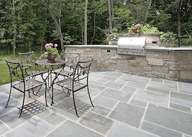 Bluestone patio and stone grill outside luxury home