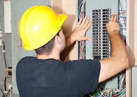 Electrician repairing circuit breakers in industrial electric panel.