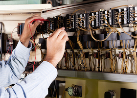 happy male electrician working on industrial machine