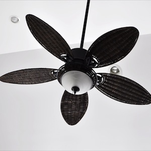 brown tropical ceiling fan against white walls with recessed lighting fixtures