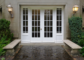 Elegant stone walkway bordered by stone benches leading to a double glass paned front door with two